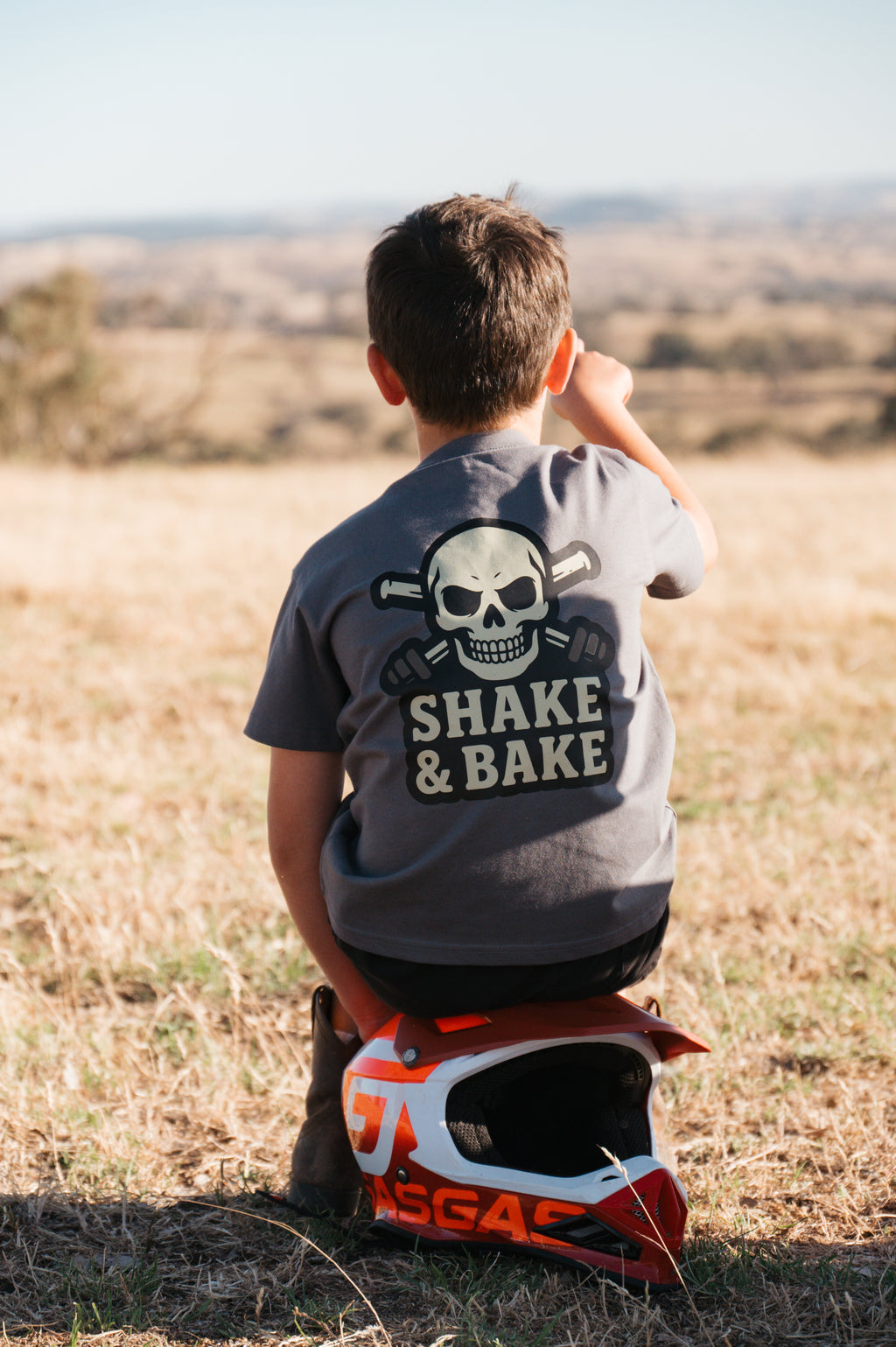 Child sitting on a motorcycle helmet with a scenic background
